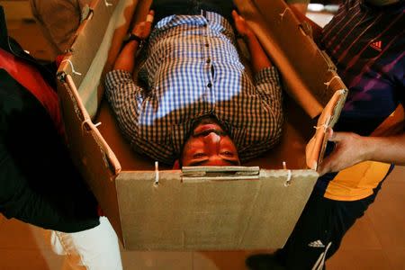Elio Angulo lies inside a cardboard coffin as he introduces his product to potential customers at a mortuary in Valencia, in the state of Carabobo, Venezuela August 25, 2016. Picture taken August 25, 2016. REUTERS/Marco Bello