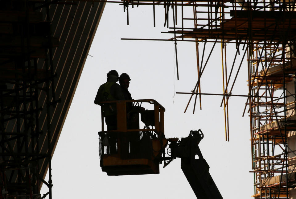 Existe una gran diferencia entre los salarios más altos del sector de la construcción y aquellos que están a la cola. En la imagen, dos trabajadores subidos en una grúa junto a un edificio en obras. REUTERS/Amr Abdallah Dalsh