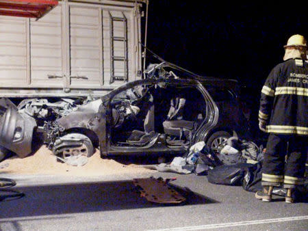 A TV still image shows a firefighter standing next to a car, trapped underneath a truck, in which three relatives of Pope Francis were killed near James Craik, Cordoba province, early August 19, 2014. REUTERS/DyN-www.noticraik.com