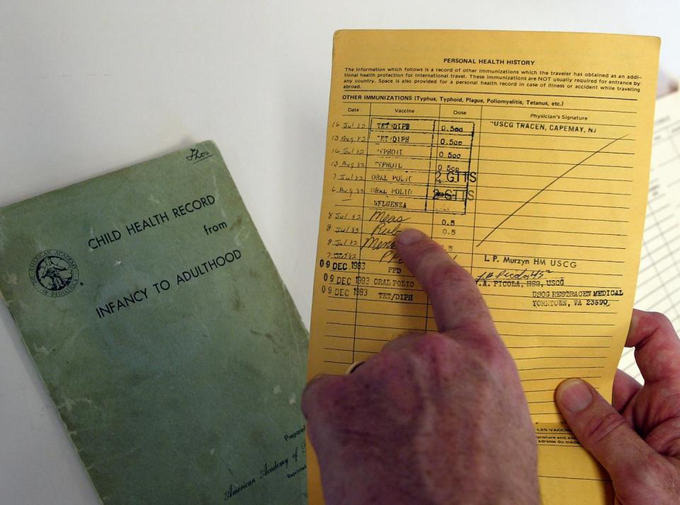 hands point to a handwritten vaccination record