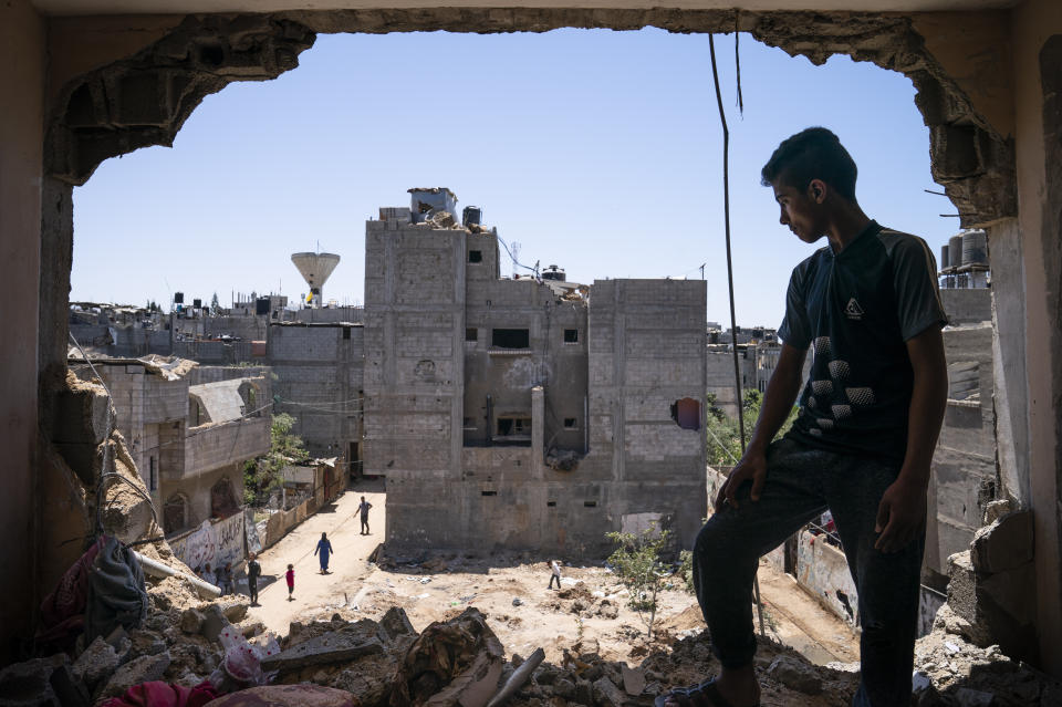 Mahmoud Al-Masri, 14, stands for a portrait in his bedroom that was damaged when an airstrike destroyed the neighboring building prior to a cease-fire that halted an 11-day war between Gaza's Hamas rulers and Israel, Wednesday, May 26, 2021, in Beit Hanoun, Gaza Strip. (AP Photo/John Minchillo)