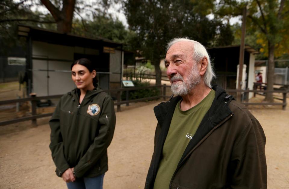 A bearded man walks with a female game warden in a clearing