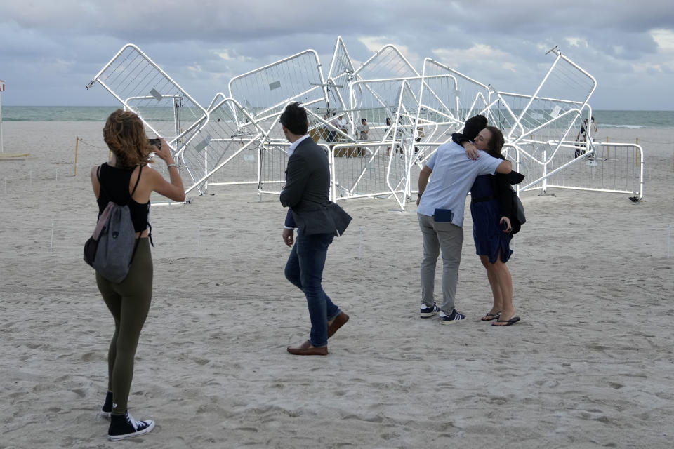 People walk past a light sculpture titled Patria y Vida created by Cuban-American artists Ruben Millares and Antonia Wright, during Miami Art Week, Thursday, Dec. 1, 2022, in Miami Beach, Fla. The sculpture is named for the anti-communism protests in Cuba. It is meant to celebrate people's right to protest, using the barricades as a symbol of global resistance. (AP Photo/Lynne Sladky)