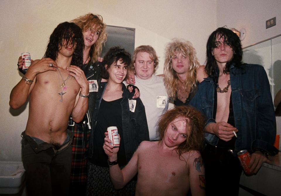 LOS ANGELES - AUGUST 30: (L-R) Slash, Duff McKagan, Teresa Ensenat (A and R for Geffen Records), Tom Zutaut (Geffen A and R), Axl Rose (seated), Steven Adler and Izzy Stradlin of the rock group 'Guns n' Roses' backstage at the Santa Monica Civic Auditorium after opening for Ted Nugent on August 30, 1986 in Los Angeles, California. (Photo by Marc S Canter/Michael Ochs Archives/Getty Images)