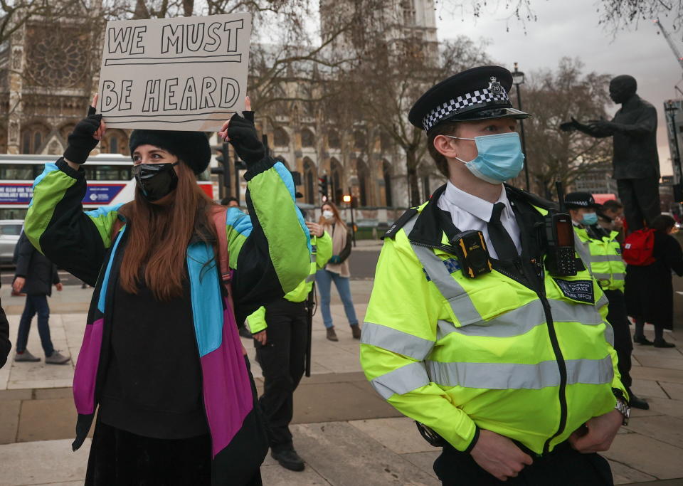 A woman holds a sign next to a police officer in Parliament Square in London.