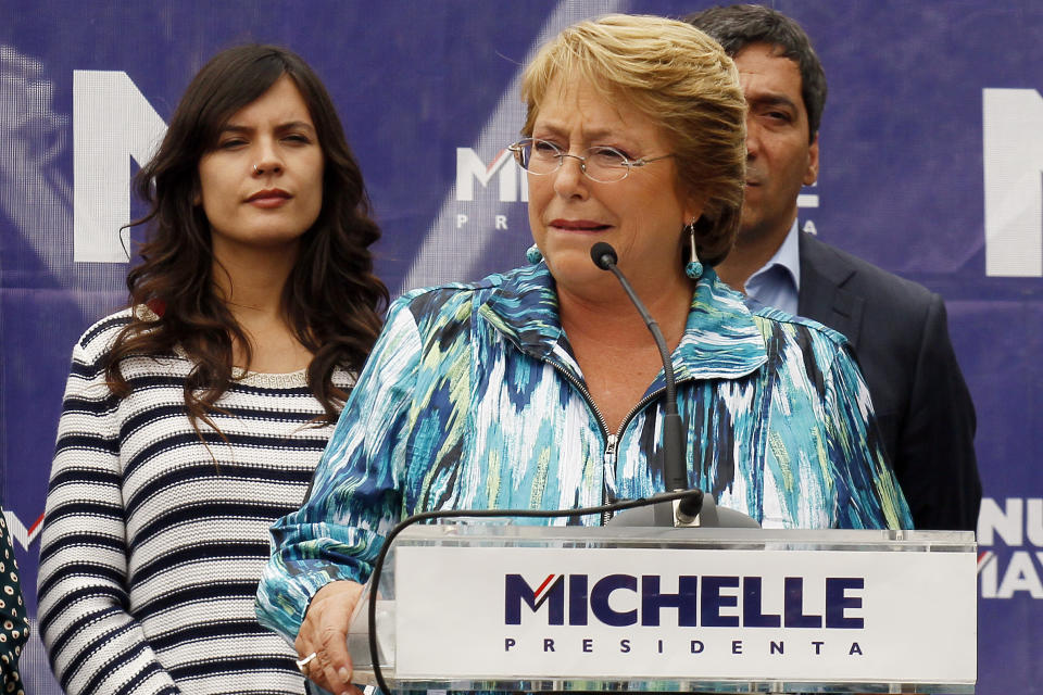 FILE - In this Nov. 19, 2013, file Photo, Chile's presidential candidate Michelle Bachelet speaks at a campaign rally in Santiago, Chile. Pictured left is newly elected member of Congress and former student leader Camila Vallejo of the Communist Party. Vallejo is now a member of Congress and a Bachelet ally, but the key university student unions are led by anarchists who are vowing to make life impossible for Bachelet if she doesn’t follow through. (AP Photo/Luis Hidalgo,File)