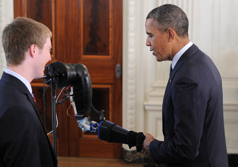 US President Barack Obama shakes a robotic hand as he  looks at science fair projects in the State Dinning Room of the White House in Washington on April 22, 2013. Obama hosted the White House Science Fair and celebrated the student winners of a broad range of science, technology, engineering and math (STEM) competitions from across the country.