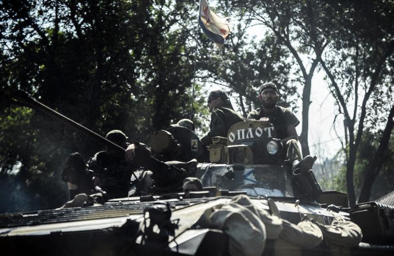 Pro-Russia militants sit on a tank as they drive towards the front line on the outskirts of Donetsk, on July 27, 2014