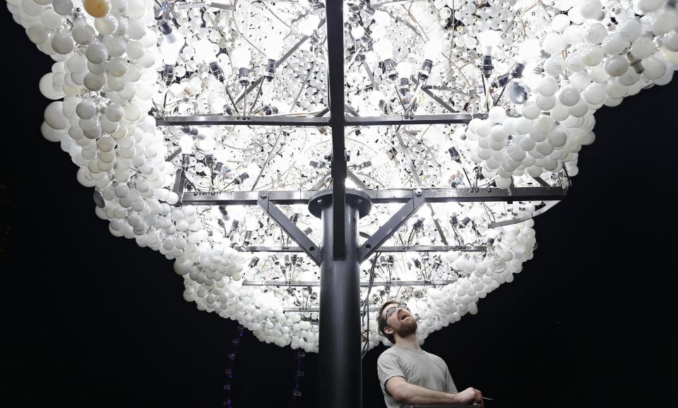 Wayne Garrett of Canada makes final touches to his art installation "CLOUD" ,made up of 5000 new and recycled lightbulbs, along the Marina Bay in Singapore