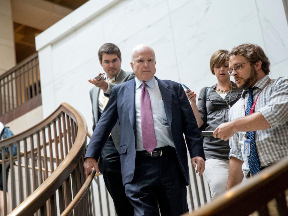 Sen. John McCain walking down the stairs in the US Capitol surrounded by reporters.