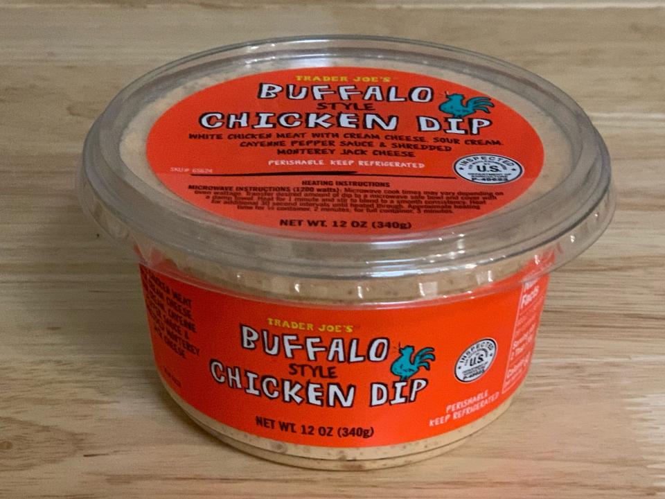 orange and clear tub of trader joe's buffalo chicken dip on wood table