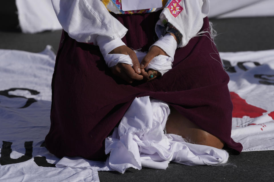 A demonstrator kneels with their hands tied as they participate in a silent protest for climate justice and human rights at the COP27 U.N. Climate Summit, Thursday, Nov. 10, 2022, in Sharm el-Sheikh, Egypt. (AP Photo/Peter Dejong)