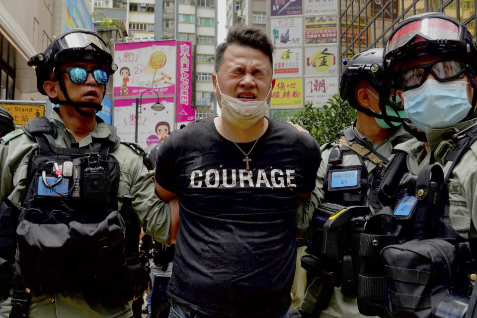 Police detain a protester after bering sprayed with pepper spray during a protest in Causeway Bay before the annual handover march in Hong Kong, Wednesday, July 1, 2020. Hong Kong marked the 23rd anniversary of its handover to China in 1997, and just one day after China enacted a national security law that cracks down on protests in the territory. (AP Photo/Vincent Yu)