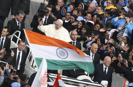 Pope Francis gestures as an Indian national flag is waved during a canonisation ceremony to make saints out of six men and women, in Saint Peter's square at the Vatican November 23, 2014. REUTERS/Alessandro Bianchi