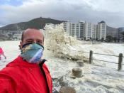 Strong wind and waves bring gusts of sea foam onto the shore in Cape Town