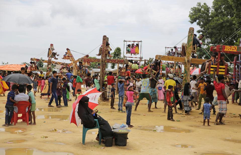 In this Aug. 23, 2018, photo, a Rohingya refugee woman sits under an umbrella as she sells fruit at a playground in Kutupalong refugee camp, Bangladesh. More than half a million Rohingya children live in the congested camps. They rely on 1,200 learning centers set up by aid organizations that can’t accommodate everyone and only offer classes up to a 5th-grade level. (AP Photo/Altaf Qadri)