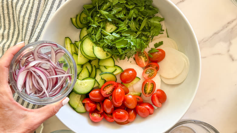 hand adding onion to bowl