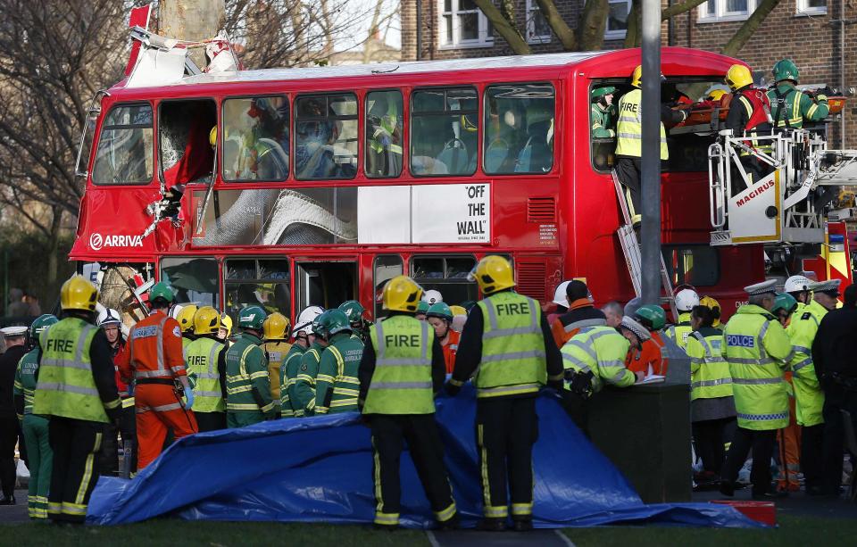 Members of the emergency services attend to a bus which crashed into a tree in Kennington, south London, December 20, 2013. 23 people were injured, two seriously, in the crash according to the Metropolitan Police. REUTERS/Suzanne Plunkett (BRITAIN - Tags: DISASTER TRANSPORT)