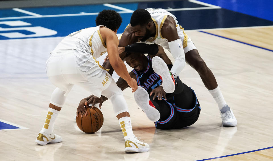 Sacramento Kings guard Delon Wright, center, battles Dallas Mavericks guard Jalen Brunson, left, and forward Tim Hardaway Jr. (11) for a loose ball during the half of a NBA basketball game, Sunday, April 18, 2021, in Dallas. (AP Photo/Brandon Wade)