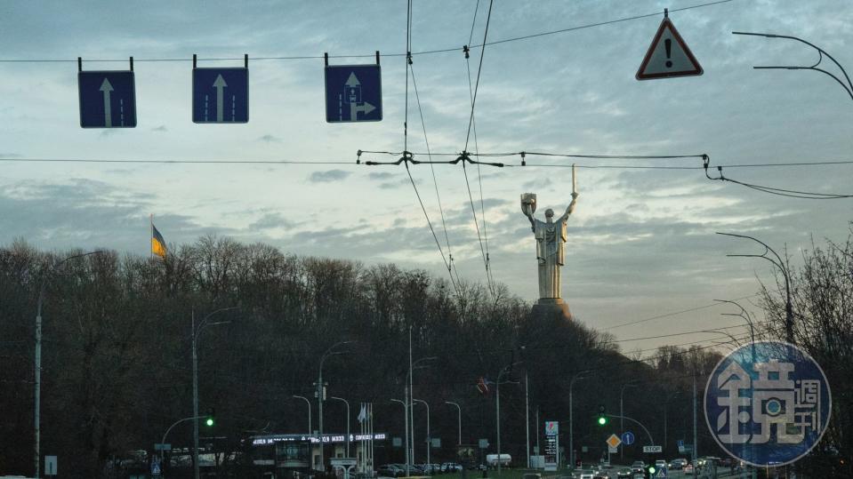 在清晨的車流中，遠處的烏克蘭母親（Mother Ukraine）紀念碑呈現極具代表性的轉變—在2023年，烏克蘭的三叉戟（Tryzub）取代了盾牌上原本的蘇聯國徽。此舉象徵烏國不斷轉變的身分和獨立狀態。