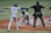 Texas Rangers' Adolis Garcia, center, looks up to see Joey Gallo (13) and home plate umpire Sam Holbrook, right, signal "safe" after a play at the plate during the seventh inning of a baseball game against the Tampa Bay Rays on Wednesday, April 14, 2021, in St. Petersburg, Fla. Garcia was ruled out after replay. (AP Photo/Steve Nesius)