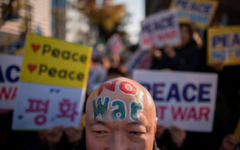 South Korean demonstrators hold placards during a peace rally in Seoul on November 5, 2017. - Credit: ED JONES/AFP