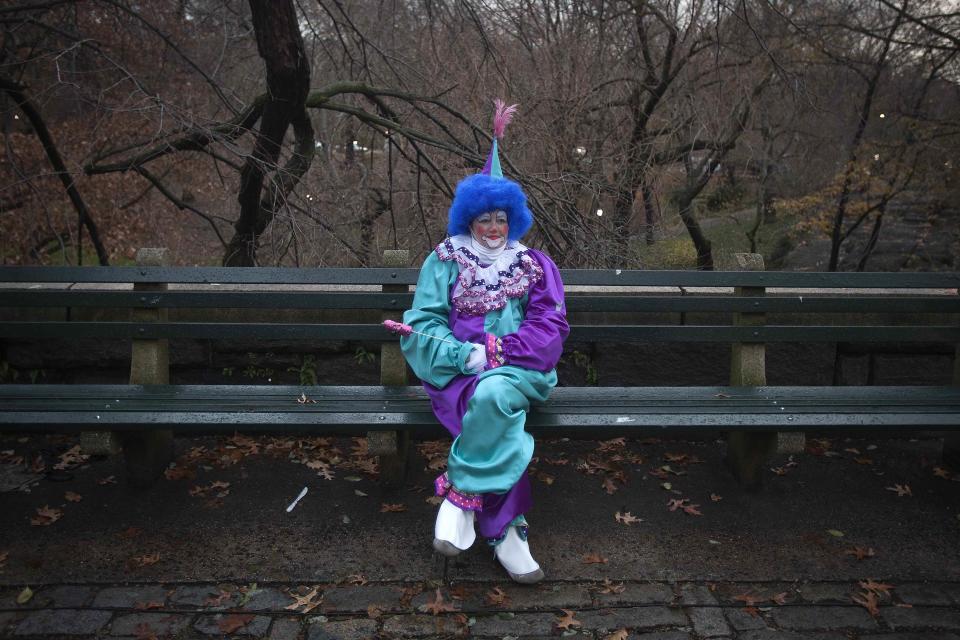 A clown sits on a park bench at sunrise before the Macy's Thanksgiving Day Parade in New York