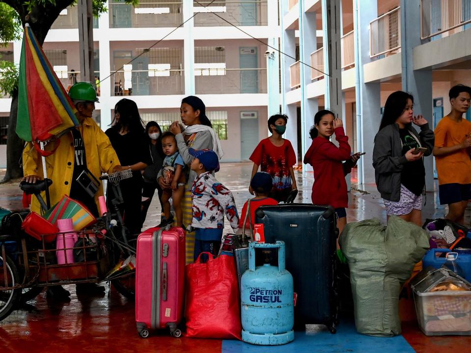 Residents with their belongings arrive at a school that serves as an evacuation centre in Marikina on October 29, 2022, following widespread flooding from heavy rain brought by Tropical Storm Nalgae.