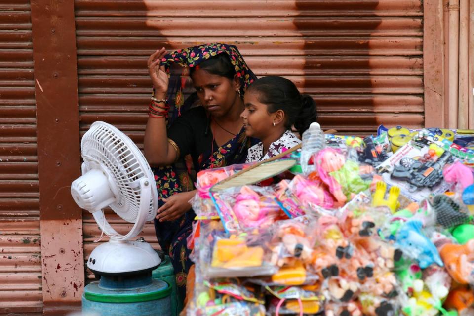 People sit in front of a table fan to cool off on a hot summer afternoon in Varanasi (AFP via Getty Images)