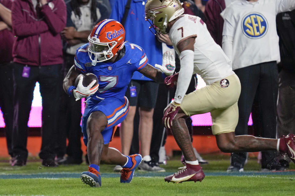 Florida running back Trevor Etienne, left, gains yardage before Florida State defensive back Jarrian Jones, right, can stop him during the first half of an NCAA college football game Saturday, Nov. 25, 2023, in Gainesville, Fla. (AP Photo/John Raoux)