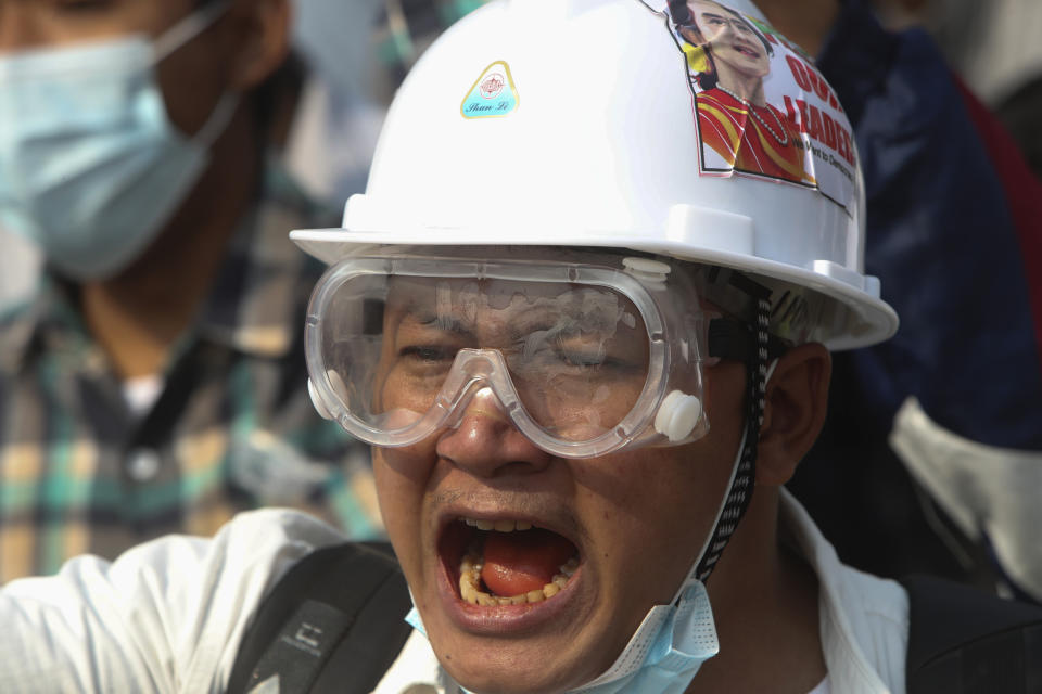 A protester wears a safety helmet and eye protector as he shouts slogans during a protest against the military coup in Yangon, Myanmar, Sunday, Feb. 28, 2021. Police fired tear gas and water cannons and there were reports of gunfire Sunday in Myanmar's largest city Yangon where another anti-coup protest was underway with scores of students and other demonstrators hauled away in police trucks. (AP Photo)