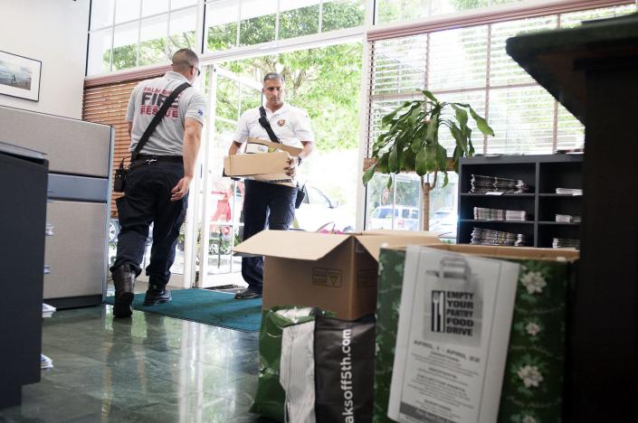 Palm Beach Fire Rescue Lt. Alex Mahy, right, and firefighter/medic Patrick Frawley carry in donated food for the Empty Your Food Pantry Drive at The Palm Beach Daily News office in 2019. CROS Ministries is one of the charities that the Town of Palm Beach United Way is helping during the coronavirus pandemic.