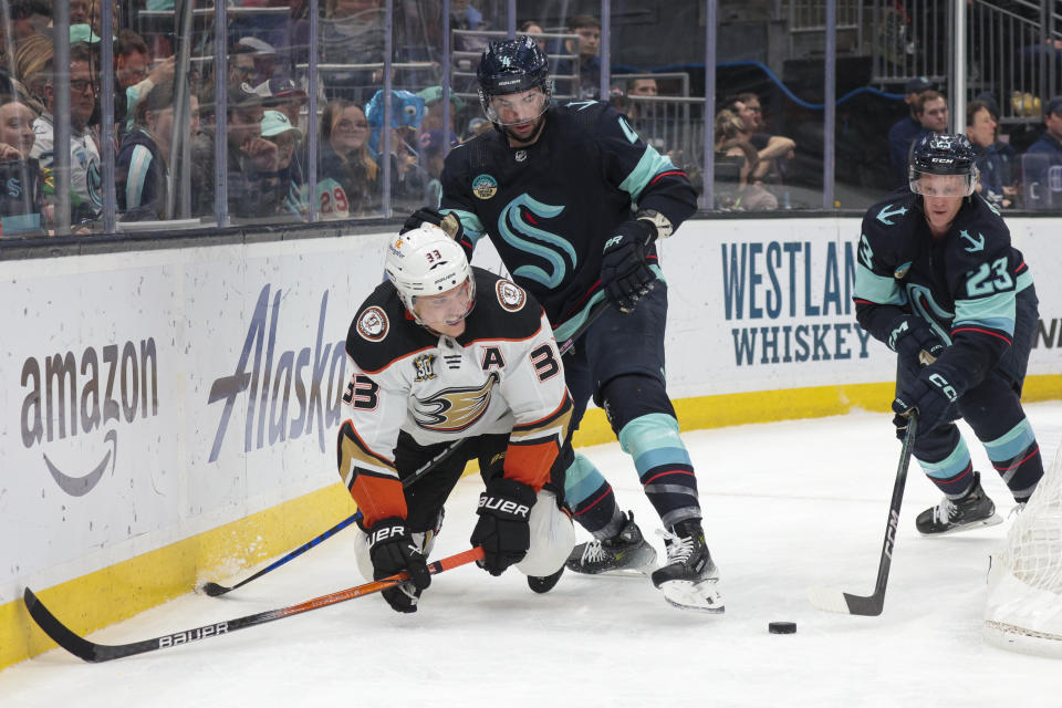 Anaheim Ducks right wing Jakob Silfverberg (33) goes for the puck as Seattle Kraken defenseman Justin Schultz (4) and defenseman Gustav Olofsson (23) defend during the second period of an NHL hockey game Tuesday, March 26, 2024, in Seattle. (AP Photo/Jason Redmond)