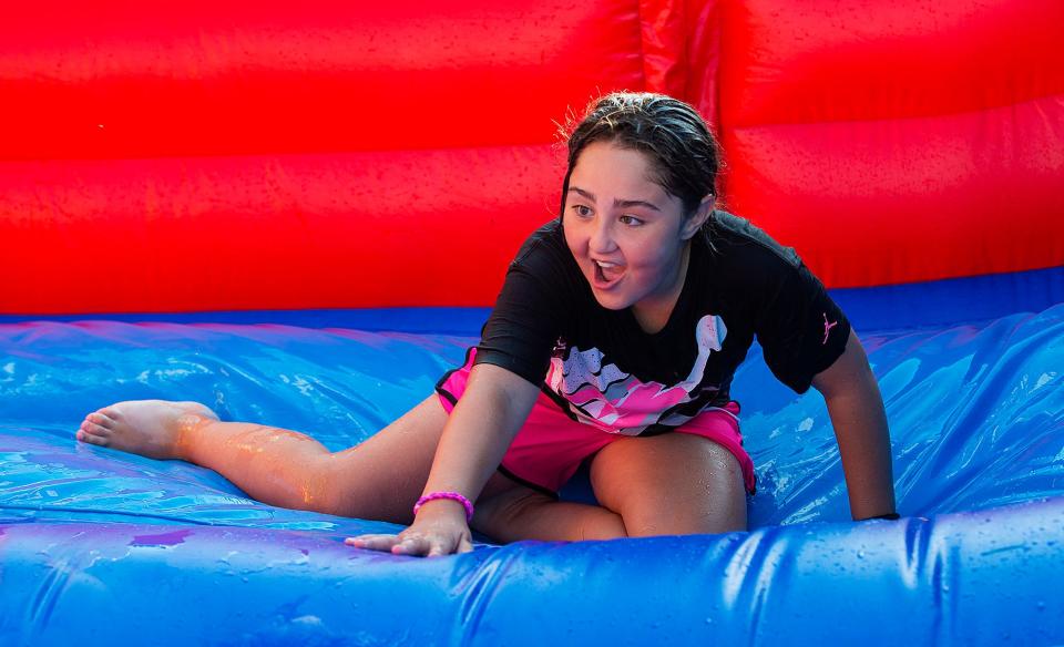 Nayaleese Rivera, 9, of Bristol Borough, reacts after coming down the water slide, during the National Night Out in Bristol Borough, which was held at the Snyder-Girotti Elementary School, on Tuesday, Aug. 2, 2022.