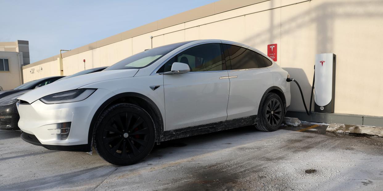 A Tesla vehicle charges in a salt and ice covered parking lot