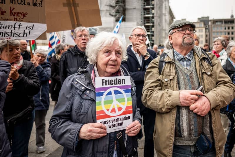 Sabine Rosenbrock (L) tient une pancarte sur la Roncalliplatz pendant la marche de Pâques sous la devise "Pour un redressement civil – mettez fin aux guerres, arrêtez le réarmement !".  Christian Knieps/dpa