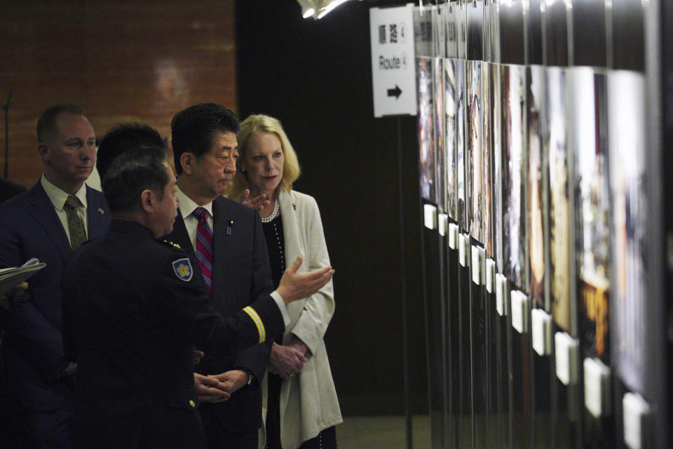Mary Jean Eisenhower, granddaughter of former U.S. President Dwight D. Eisenhower, right, and Merrill Eisenhower Atwater, the great-grandson, left, with Japan's Prime Minister Shinzo Abe, are guided to see a photo exposition on the 60th Anniversary commemorative reception of the signing of the Japan-U.S. Security Treaty at the Iikura Guesthouse in Tokyo Sunday, Jan. 19, 2020. (AP Photo/Eugene Hoshiko, Pool)