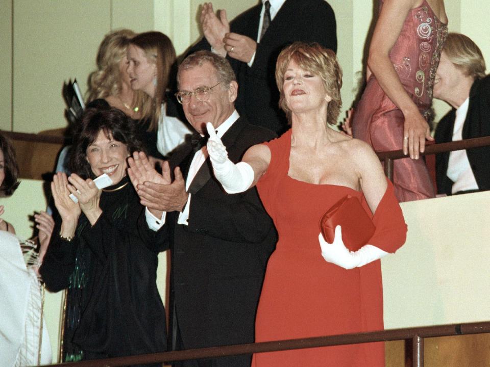 Jane and Tomlin clapping and waving on a balcony in a theater.