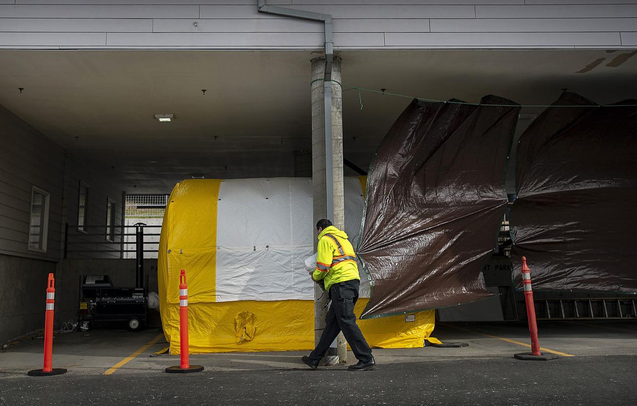 A hospital worker transfers equipment to a curbside testing area at PeaceHealth Ketchikan Medical Center in Ketchikan, Alaska, Wednesday, March 18, 2020. The testing area is set for patients showing symptoms after potential contact with the new coronavirus that causes COVID-19. PeaceHealth is providing curbside tests only to patients with a referral from the Ketchikan Public Health Center.