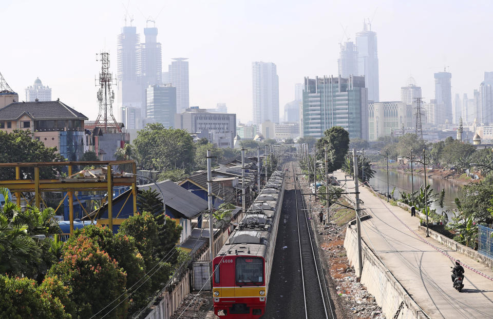 A train moves down its track as the hazy city skyline is seen in the background in Jakarta, Indonesia, Thursday, Sept. 16, 2021. An Indonesian court ruled Thursday that President Joko Widodo and six other top officials have neglected to fulfill citizens' rights to clean air and ordered them to improve the poor air quality in the capital. (AP Photo/Tatan Syuflana)