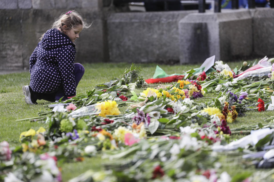 A child looks at flowers outside of Windsor Castle in Windsor, England after the announcement regarding the death of Britain's Prince Philip, Friday, April 9, 2021. Buckingham Palace officials say Prince Philip, the husband of Queen Elizabeth II, has died. He was 99. Philip spent a month in hospital earlier this year before being released on March 16 to return to Windsor Castle. (AP Photo/Kirsty Wigglesworth)