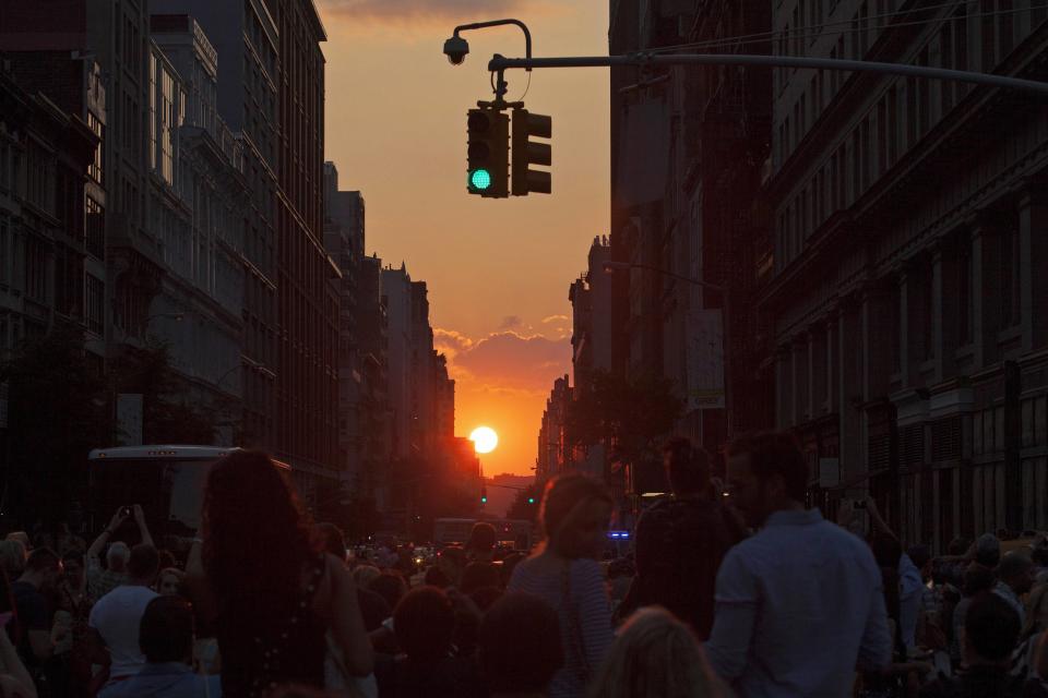 People take pictures at sunset during the bi-annual occurrence "Manhattanhenge" in New York