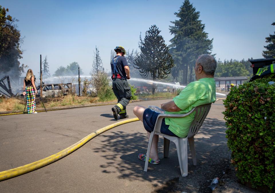 Chris Beltran sits and watches the smoldering rubble fo his home after a fire tore through it and at least one other on Kremont Avenue in Springfield Sunday.