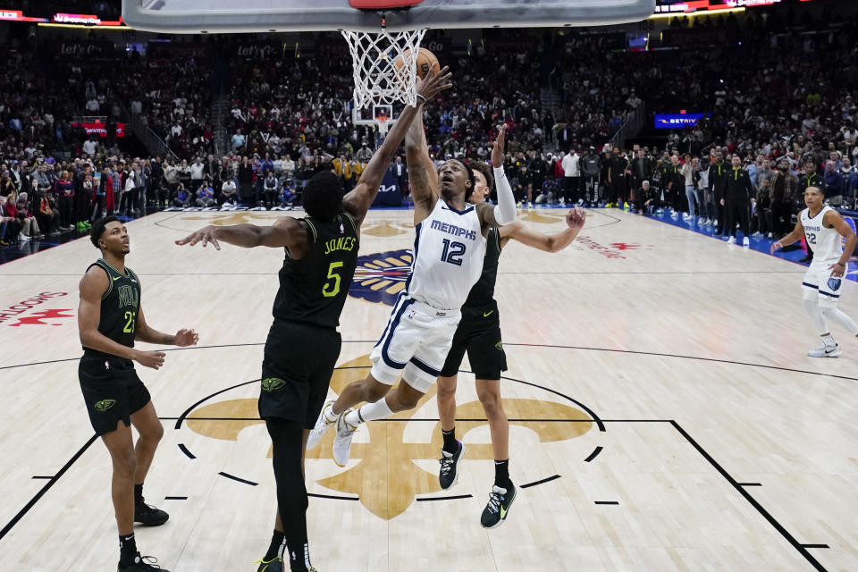 Memphis Grizzlies guard Ja Morant (12) goes to the basket between New Orleans Pelicans forward Herbert Jones (5) and guard Dyson Daniels for the game winning shot at the buzzer in the second half of an NBA basketball game in New Orleans, Tuesday, Dec. 19, 2023. The Grizzlies won 115-113. (AP Photo/Gerald Herbert)