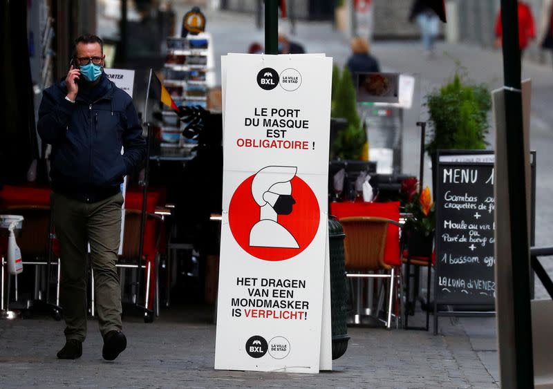 A man walks past a sign announcing the mandatory use of masks amid the coronavirus disease outbreak in Brussels