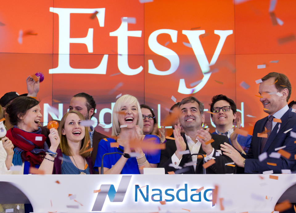 FILE - In this April 16, 2015 file photo, Kristina Salen, center left, Etsy’s Chief Financial Officer, stands with Chad Dickerson, center right, Chairman and Chief Executive Officer of Etsy, to celebrate the company's IPO with employees and guests at the Nasdaq MarketSite, in New York. There’s an emphasis on craftiness this holiday. But there’s no need to slave away with knitting needles or the glue gun. It’s easier than ever to give crafty gifts without lifting a finger - except for a few clicks of the mouse. The $30 billion crafting market has been heating up since craft-selling site Etsy debuted as a public company in April. Etsy, Amazon, eBay and others are all stepping up their homemade offerings just in time for Christmas. (AP Photo/Mark Lennihan, File)