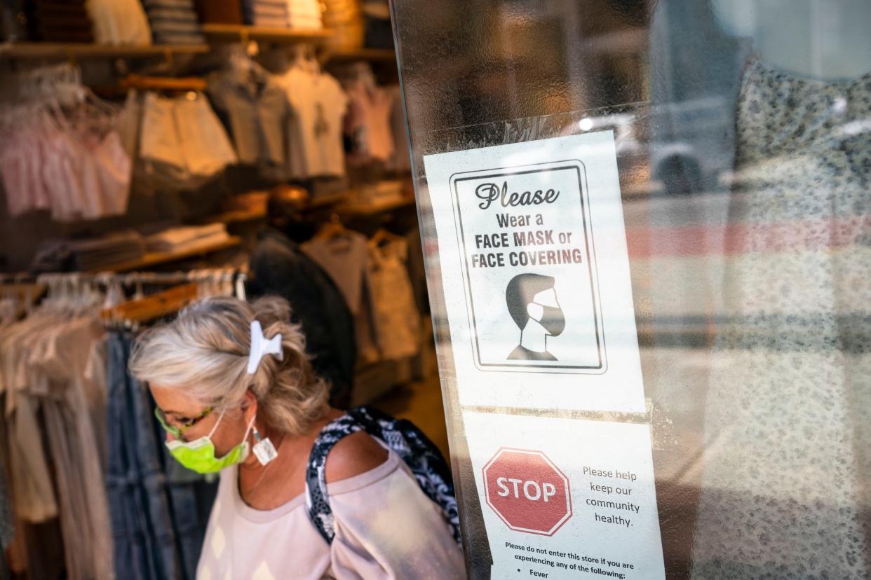 A customer wearing a protective mask exits a store on Broadway in the retail shopping district of the SoHo neighborhood of the Manhattan borough of New York.