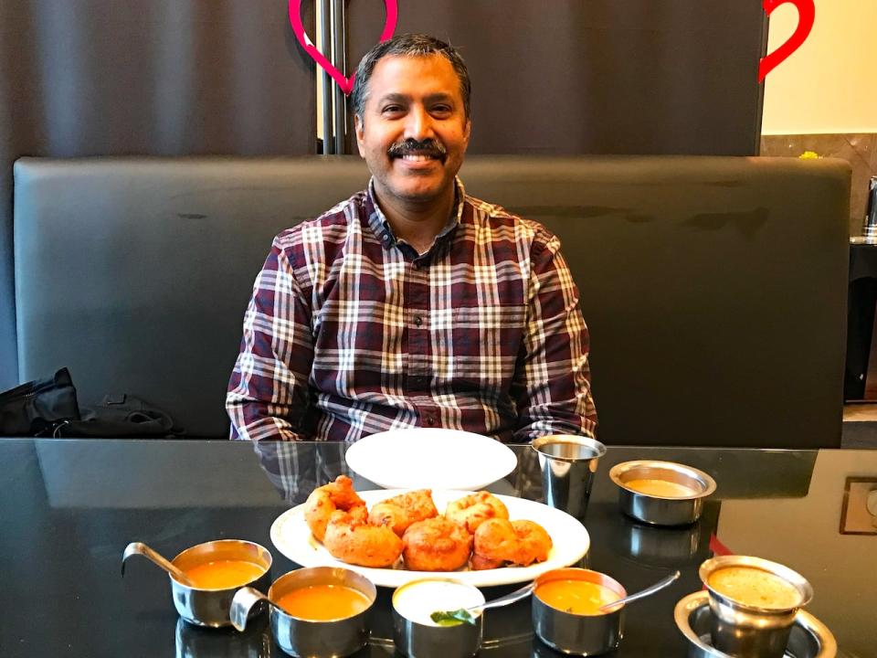 Dennis Loyola, of the Tamil Cultural Association of Waterloo Region, sits in front of a platter of vadai (daal fritters) a traditional food served during Puthandu (Tamil New Year).