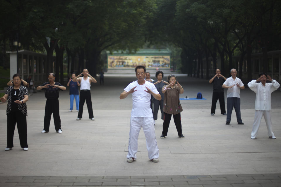 In this Tuesday, July 17, 2012 photo, people practice qigong, a traditional Chinese practice using meditation and martial arts exercises to channel unseen forces and improve health, during their morning exercise at Ritan Park in Beijing, China. Some of the bigger parks in Beijing charge admission, but not Ritan Park, the historic garden where emperors once made offerings to the sun in an ancient circular wall-enclosed altar. (AP Photo/Alexander F. Yuan)