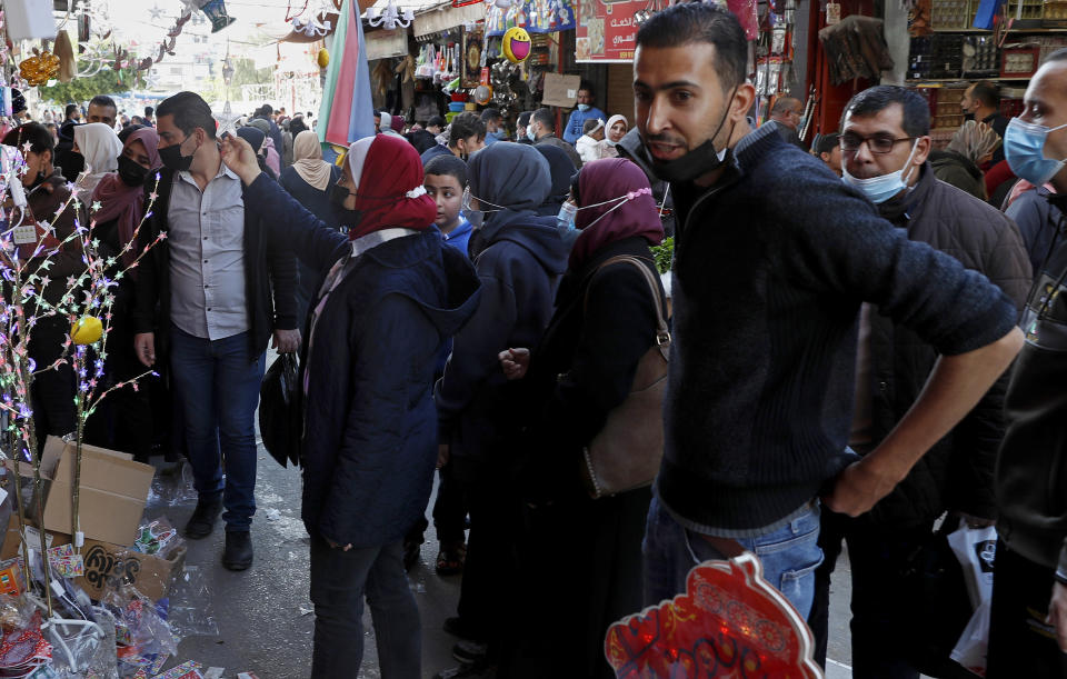 People, some wearing masks to help prevent the spread of the coronavirus, shop for the Muslim holy month of Ramadan, at the main market in Gaza City, Sunday, April 11, 2021. More than a year into the coronavirus pandemic, the worst fears are now coming true in the crowded, blockaded Gaza Strip: A sudden surge in infections and deaths is threatening to overwhelm hospitals weakened by years of conflict and Israeli border closures. (AP Photo/Adel Hana)